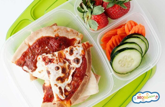sliced pita pizza in a lunch container with strawberries, cucumber, and carrots.