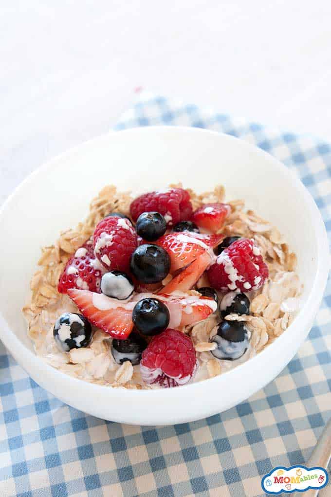 Image: a bowl of oats topped with fresh berries and milk.