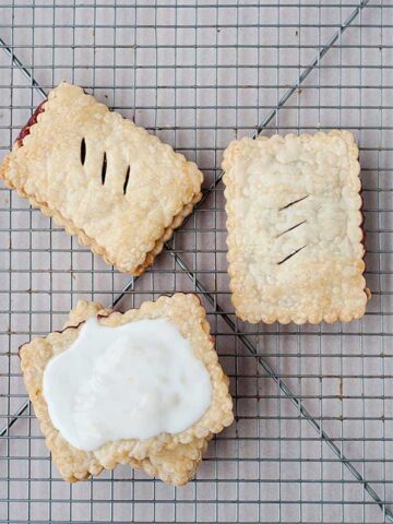 overhead view of three gluten free pop tarts on a baking sheet, one frosted