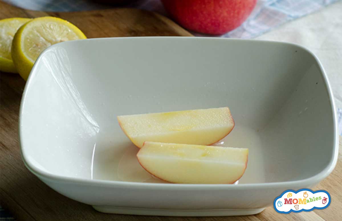 apple slices in a white bowl with lemon juice