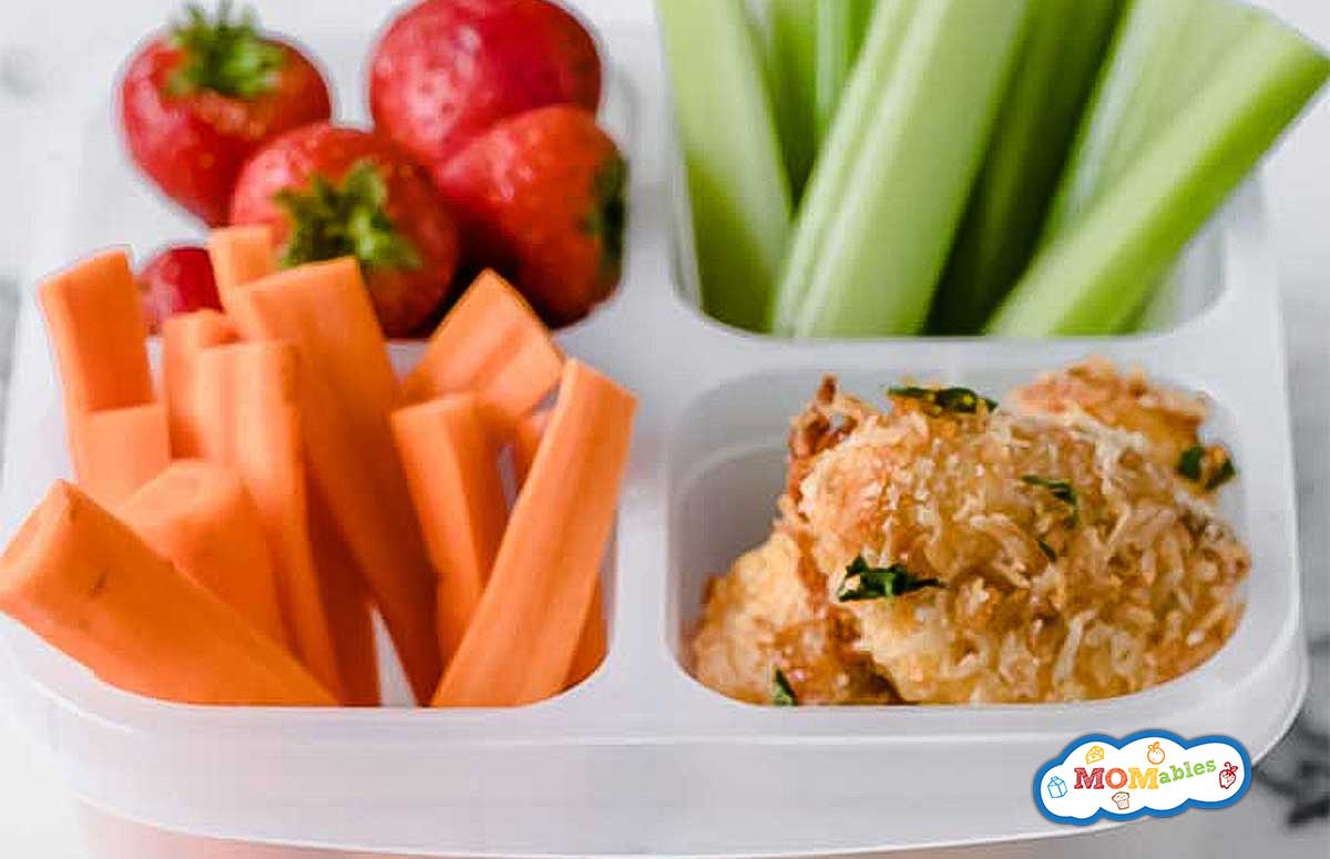a lunch container filled with chicken nuggets, veggies, and strawberries