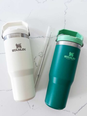 two stanley bottles and straws and straw cleaner on counter