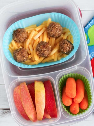 tuna balls and macaroni and cheese in a lunch container with fruits and veggies