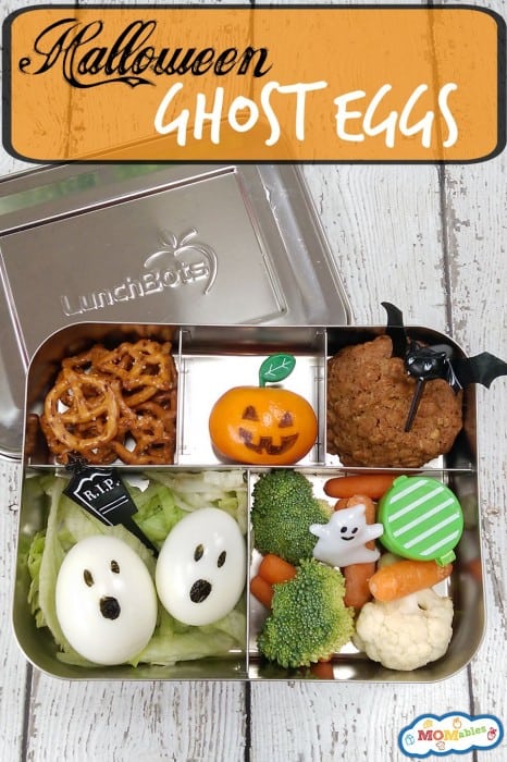 Image: Halloween ghost eggs packed in a lunch container with veggies, a baked cookie, orange, and pretzels. 