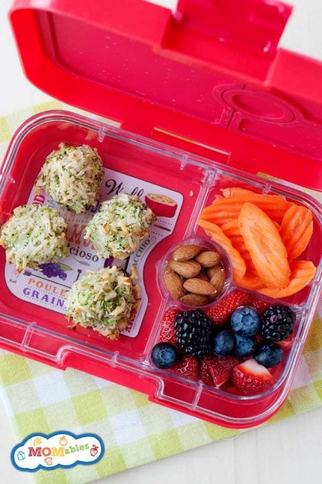 broccoli tater tots in a pink lunch container with fruit, sliced carrots and almonds