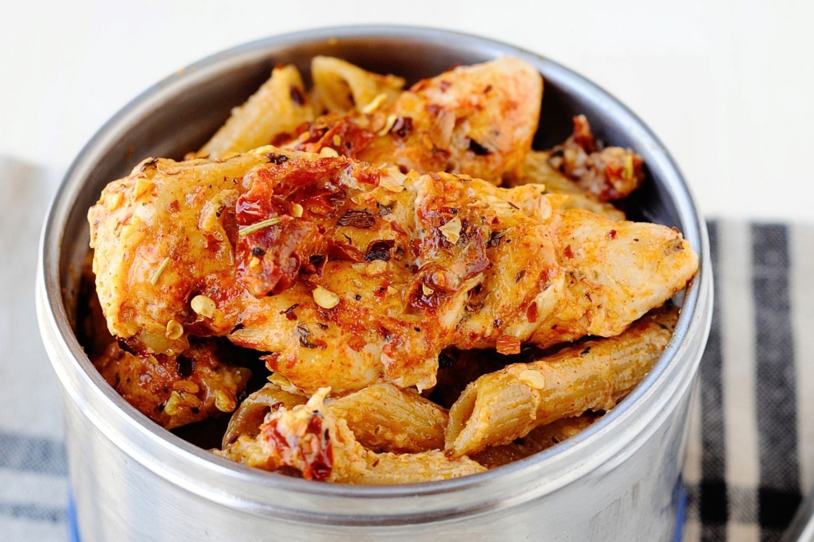 thermos container filled with pasta and sun-dried tomato sauce