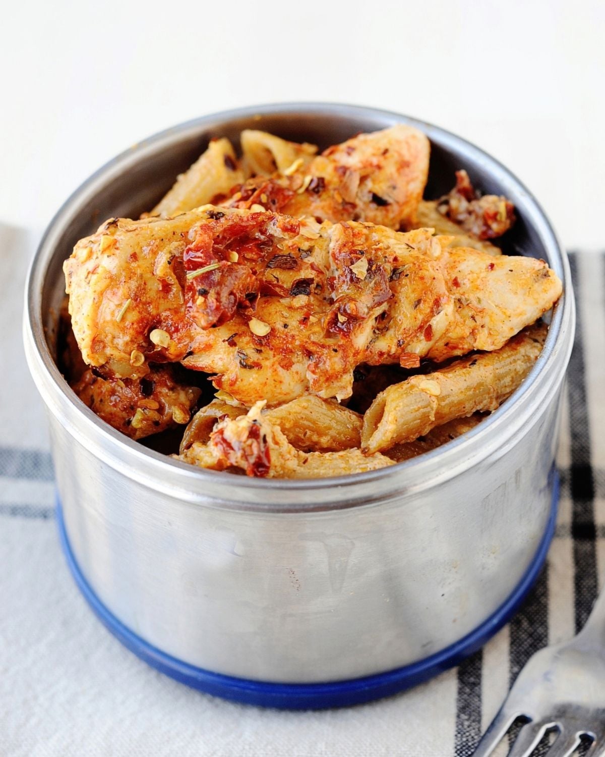thermos container filled with pasta and sun-dried tomato sauce