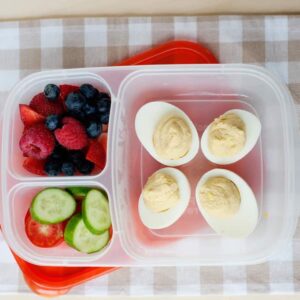 Deviled eggs, cucumber, tomato, and berries in a compartment lunch container