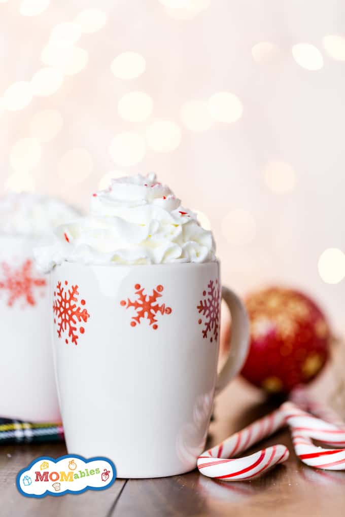 Image: chocolat chaud à la menthe poivrée dans une tasse blanche garnie de crème fouettée et de cannes de bonbons hachées.