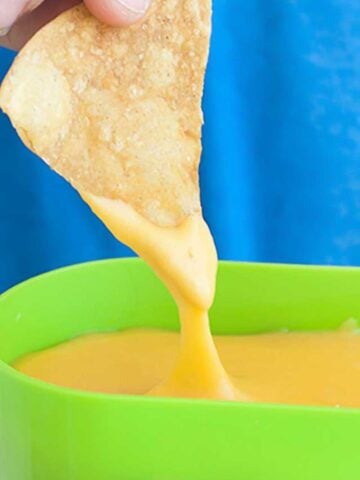 a chip being dipped into cheese sauce