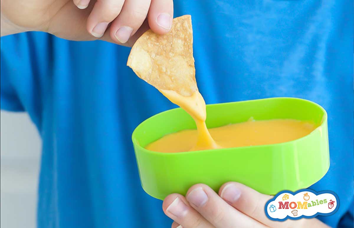 a chip being dipped into cheese sauce