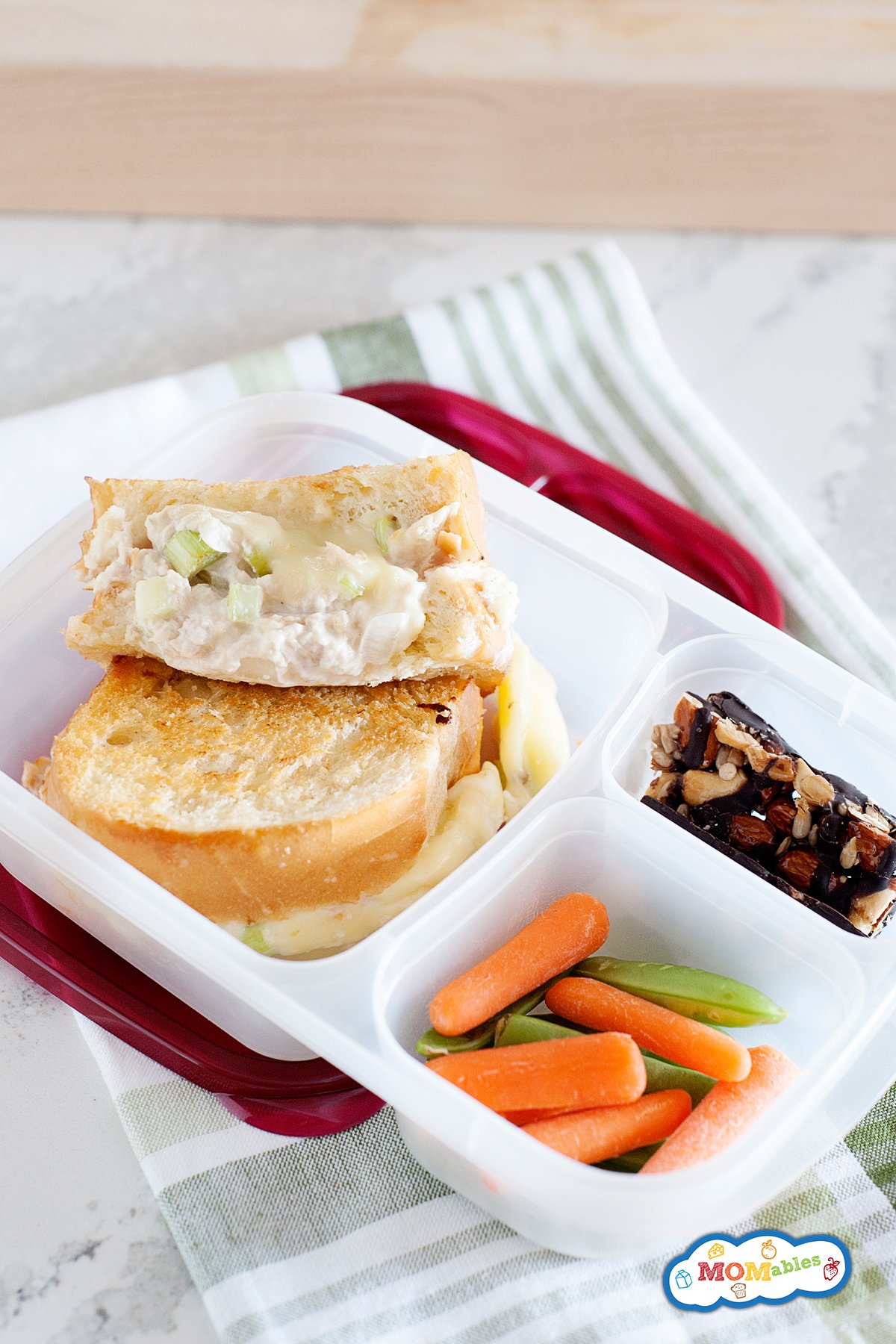 grilled tuna melt sandwich in a lunch container with baby carrots and snap peas