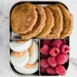 mini pumpkin pancakes in a metal lunchbox with raspberries and hard boiled eggs