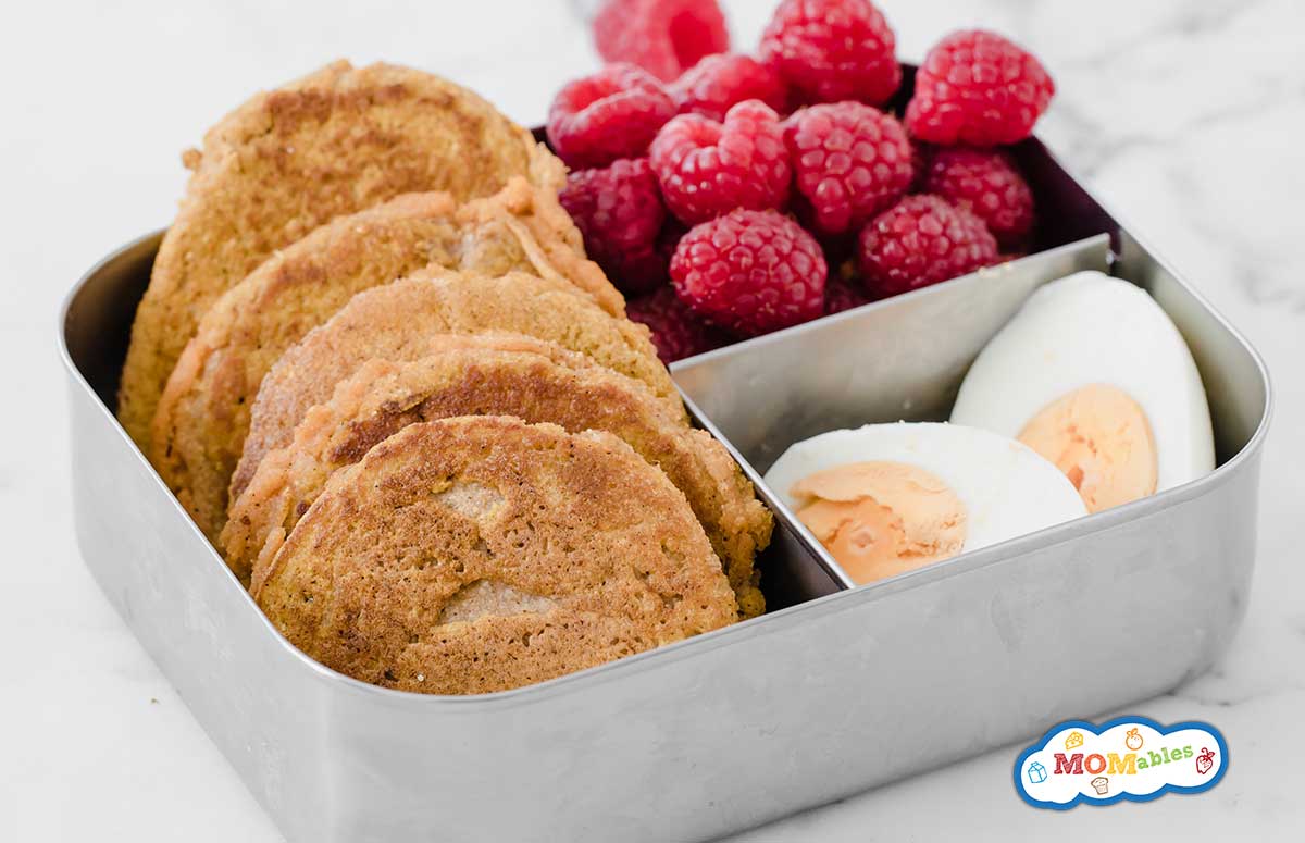 mini pumpkin pancakes in a metal lunchbox with raspberries and hard boiled eggs
