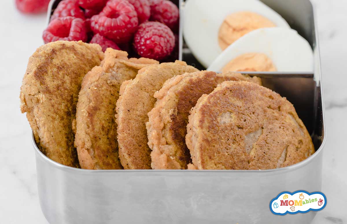 mini pumpkin pancakes in a metal lunchbox with raspberries and hard boiled eggs