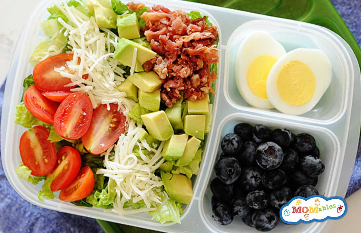 image: BLT salad in a lunchbox container. Included in the container is sliced boiled eggs and blueberries.