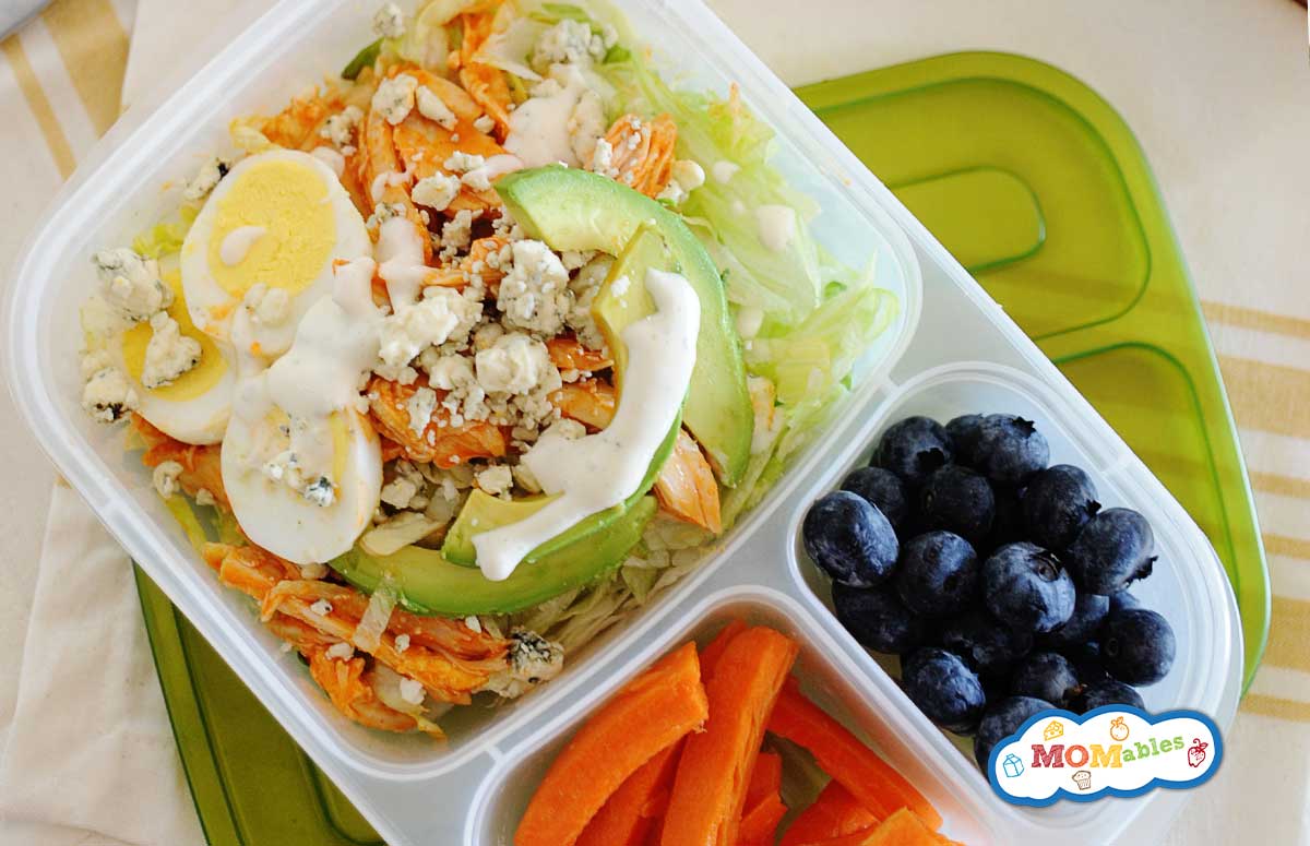 Buffalo Chicken Salad with dressing in a divided lunch container. Carrot sticks and blueberries fill the other two container sides
