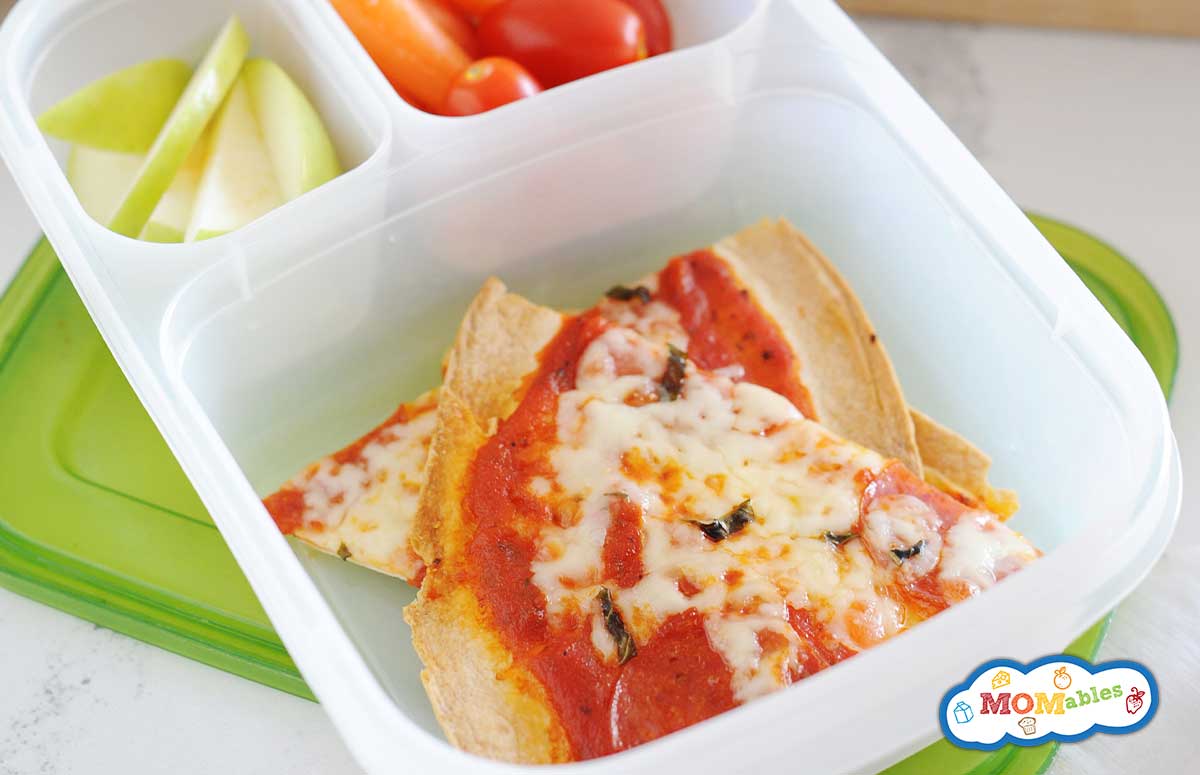 tortilla pizza in a lunch box with tomatoes, baby carrots and apple slices