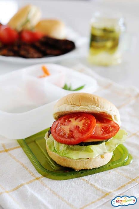 Image: a black bean veggie burger on a bun with lettuce and tomatoes.