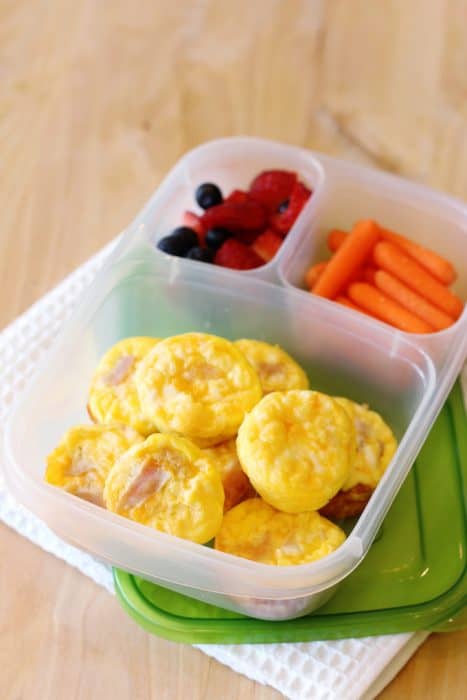 image: lunch container with 9 mini quiches, strawberries and carrot sticks.