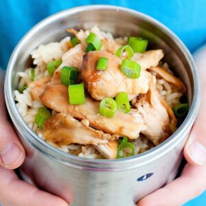 child holding small thermos of teriyaki chicken