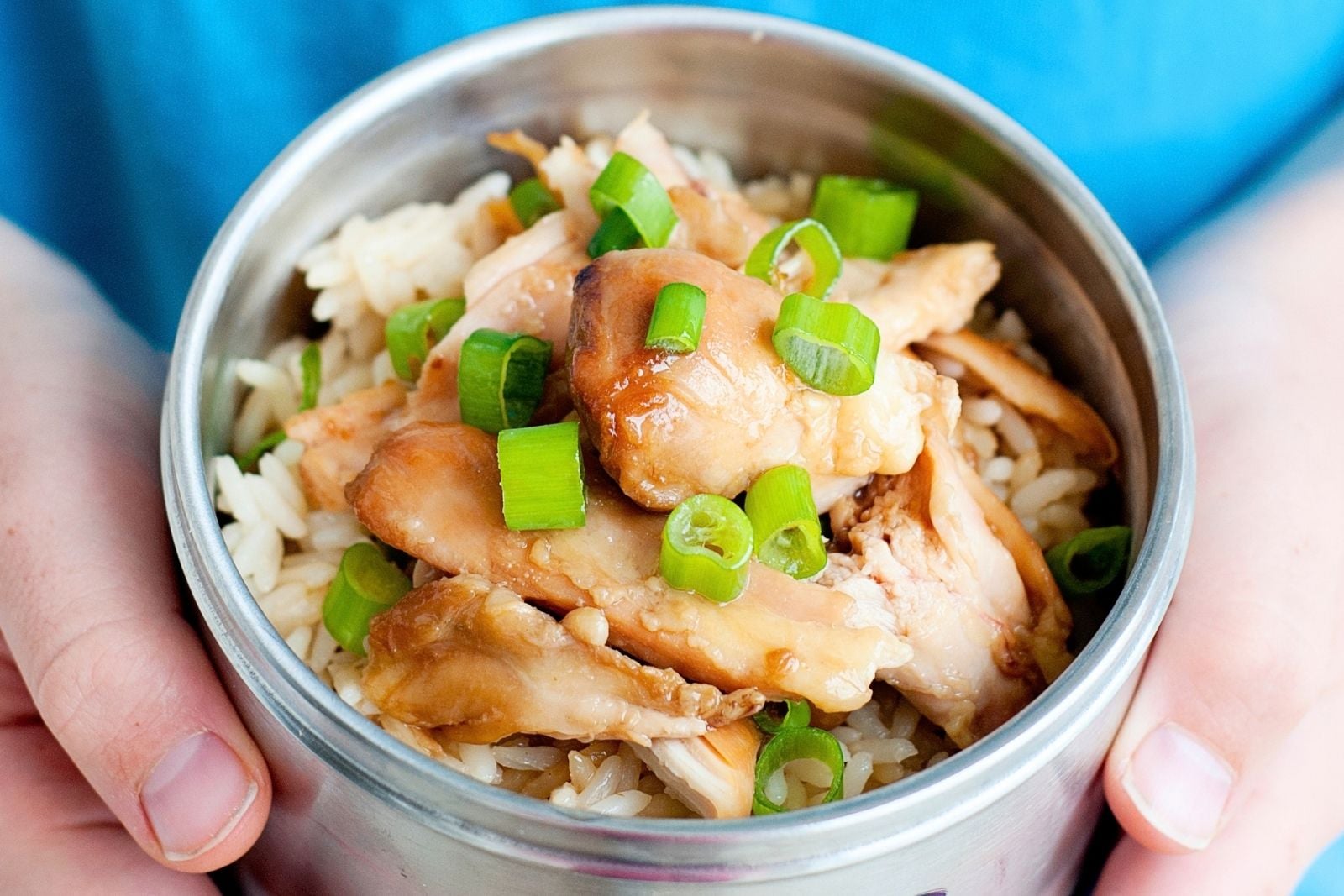 child holding small thermos of teriyaki chicken
