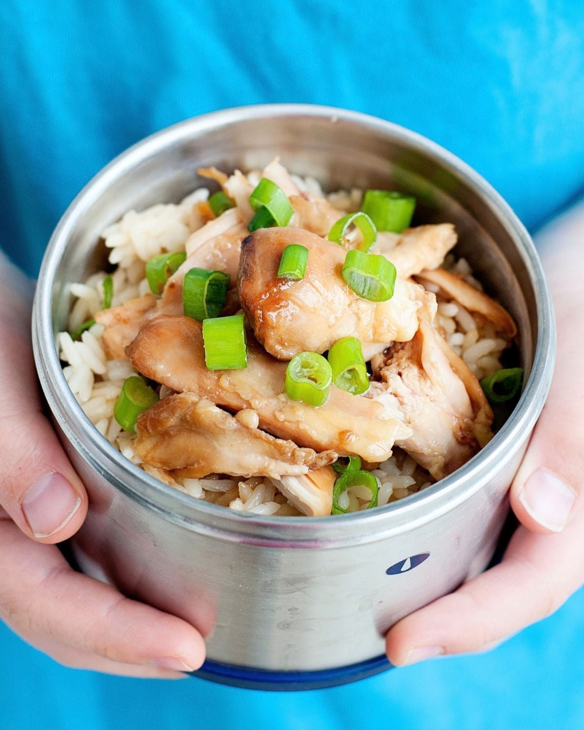 child holding small thermos of teriyaki chicken