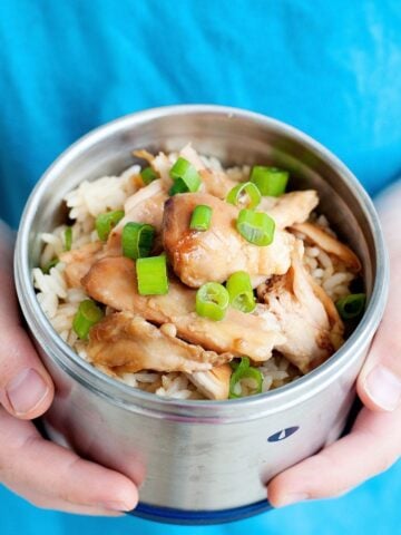 child holding small thermos of teriyaki chicken