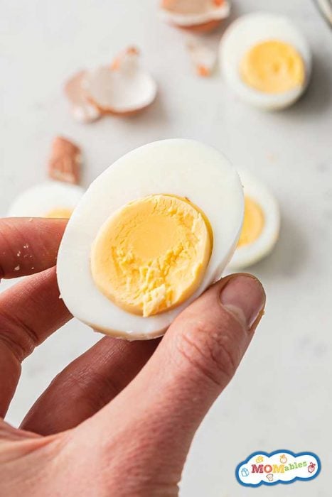 half a hard boiled egg being held above countertop