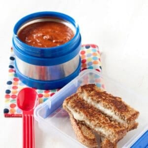 a lunchbox with cheese dippers and a thermos with tomato soup