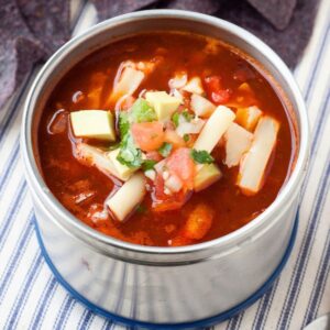 thermos of enchilada soup with shredded cheese on top