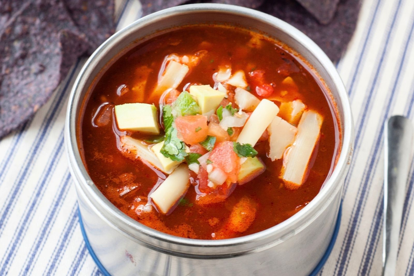 thermos of enchilada soup with shredded cheese on top