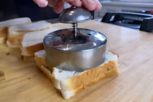 using a bread crimper to cut out a homemade uncrustable on a wooden board