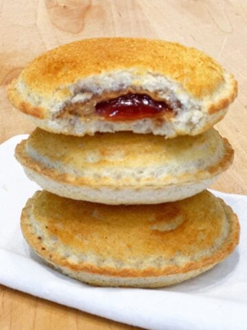 a stack of three uncrustables stacked on top of each other. They are golden and crisp because they've been toasted in the air fryer