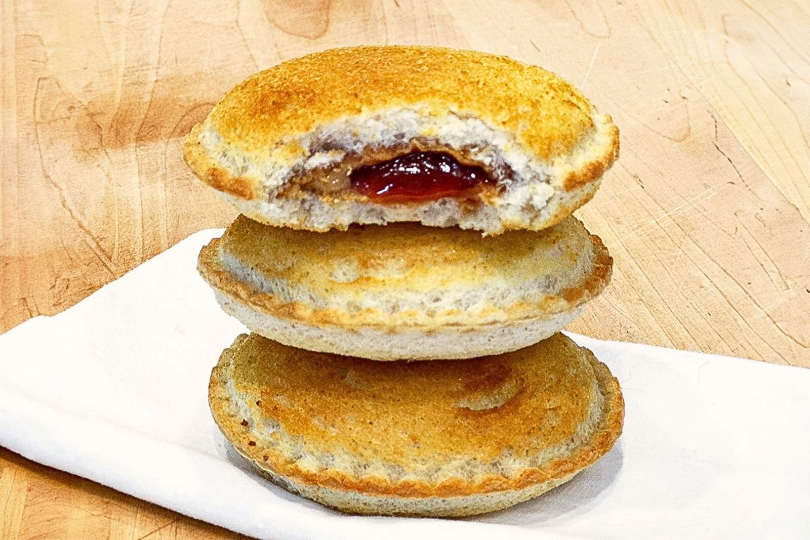 a stack of three uncrustables stacked on top of each other. They are golden and crisp because they've been toasted in the air fryer