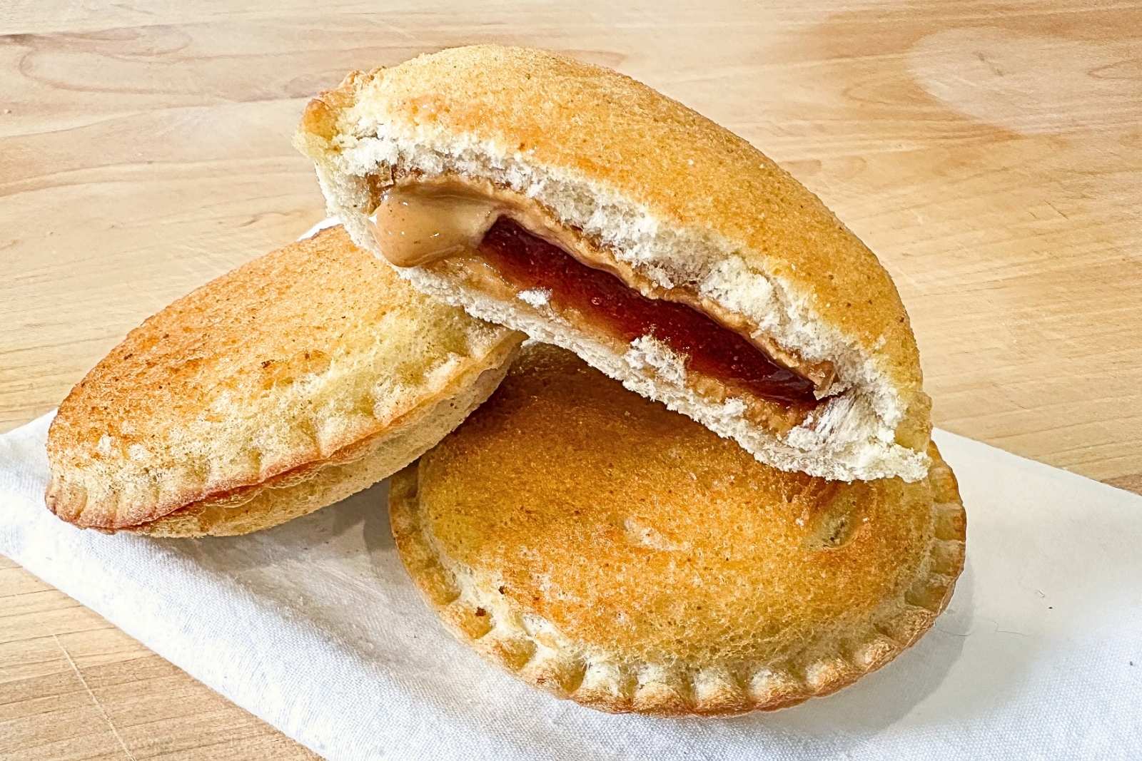 a stack of three uncrustables stacked on top of each other. They are golden and crisp because they've been toasted in the air fryer