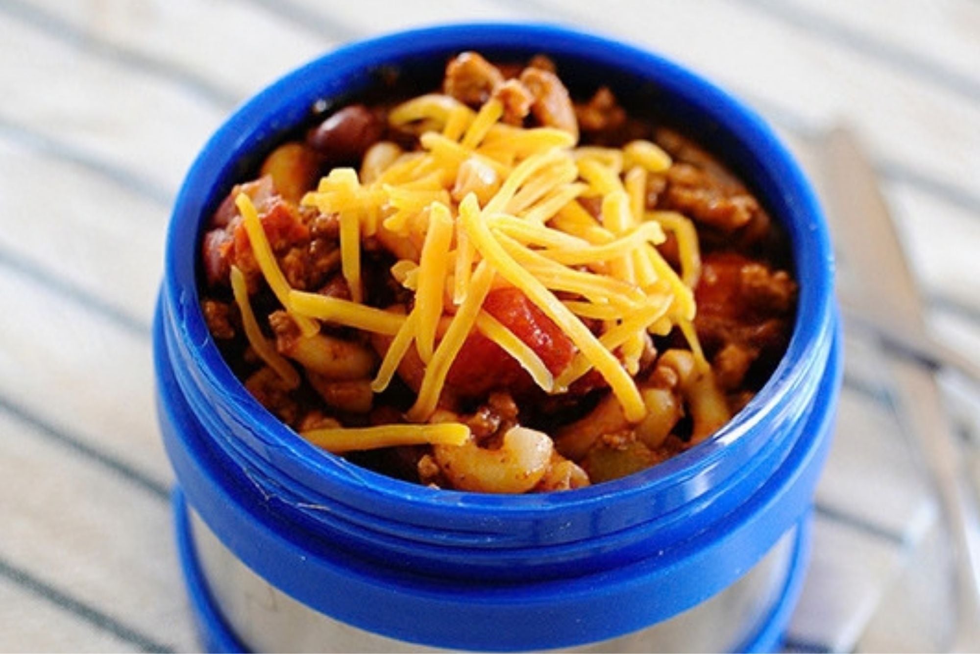 chili mac topped with cheese in a thermos