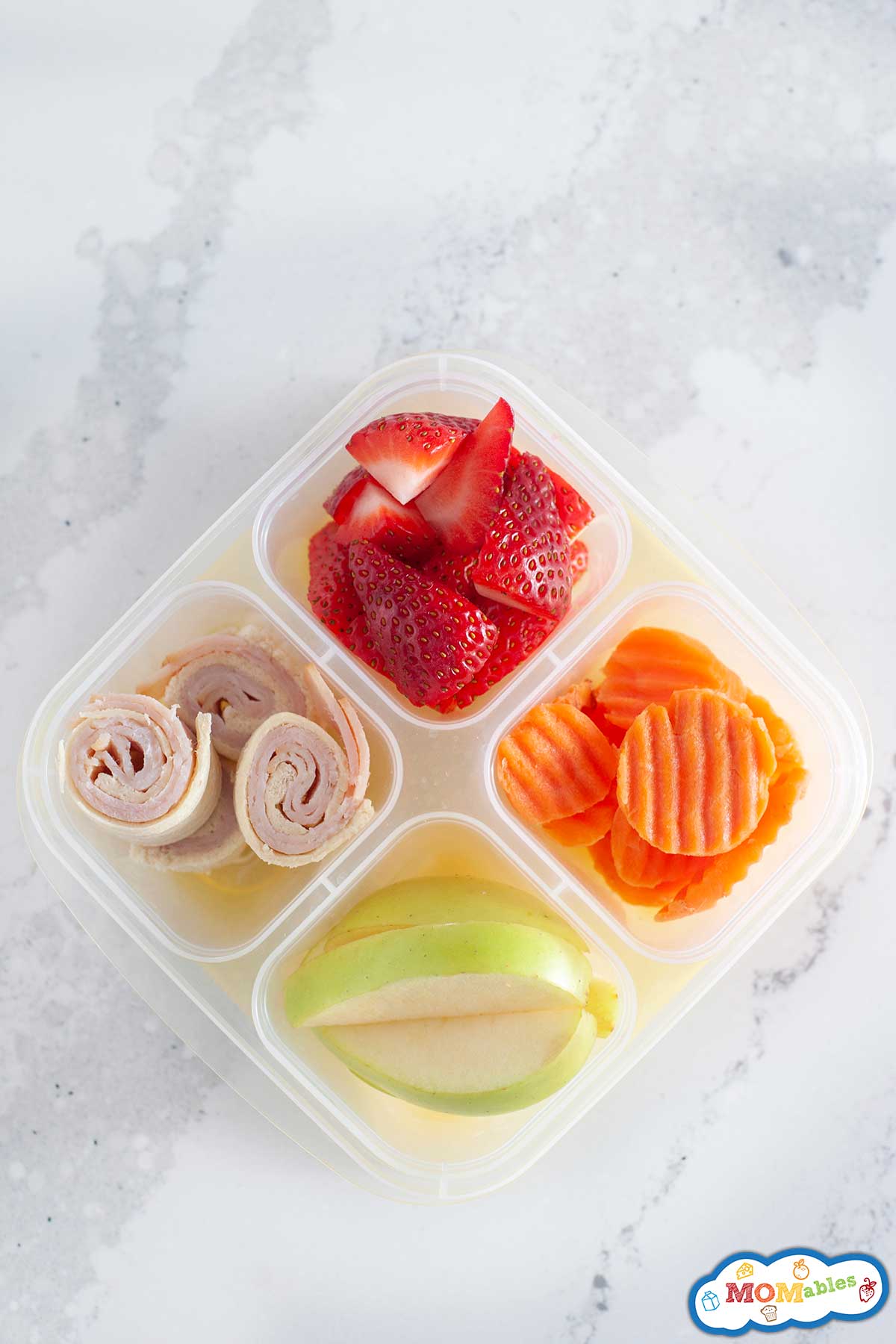 Ham roll ups in a lunch container with fruit and veggies.