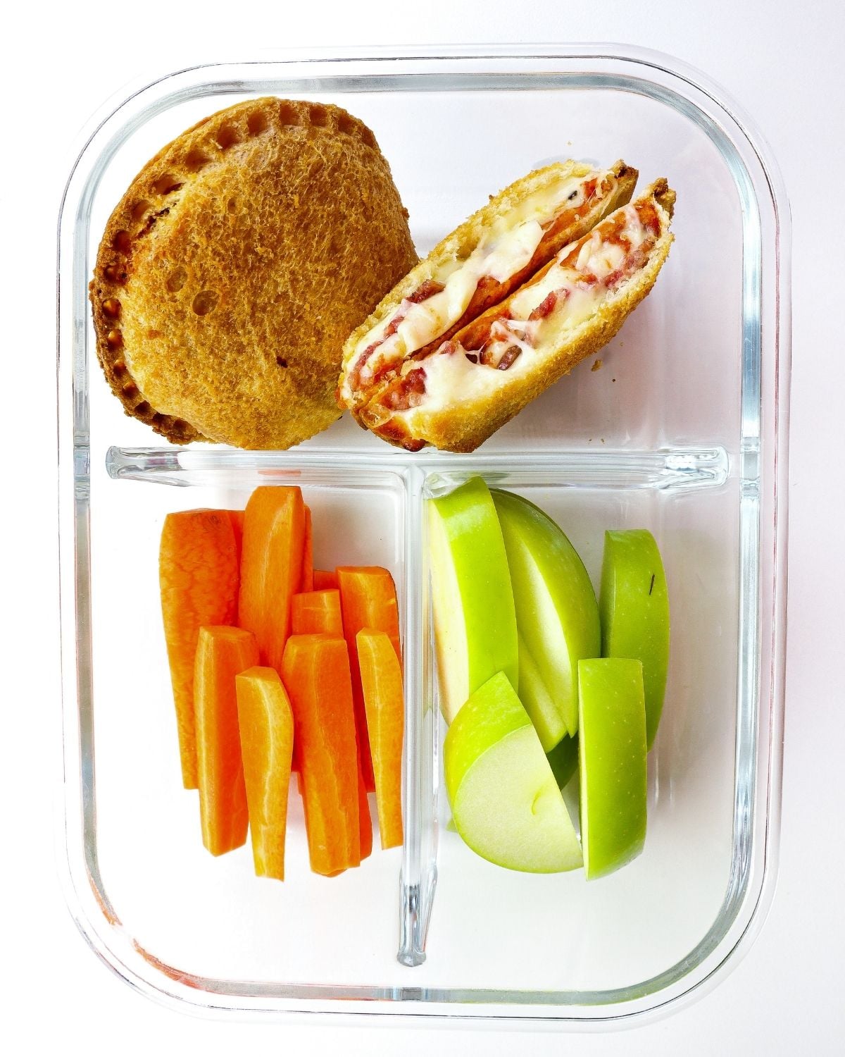 pizza uncrustable packed into a lunch container with sliced apples and carrots