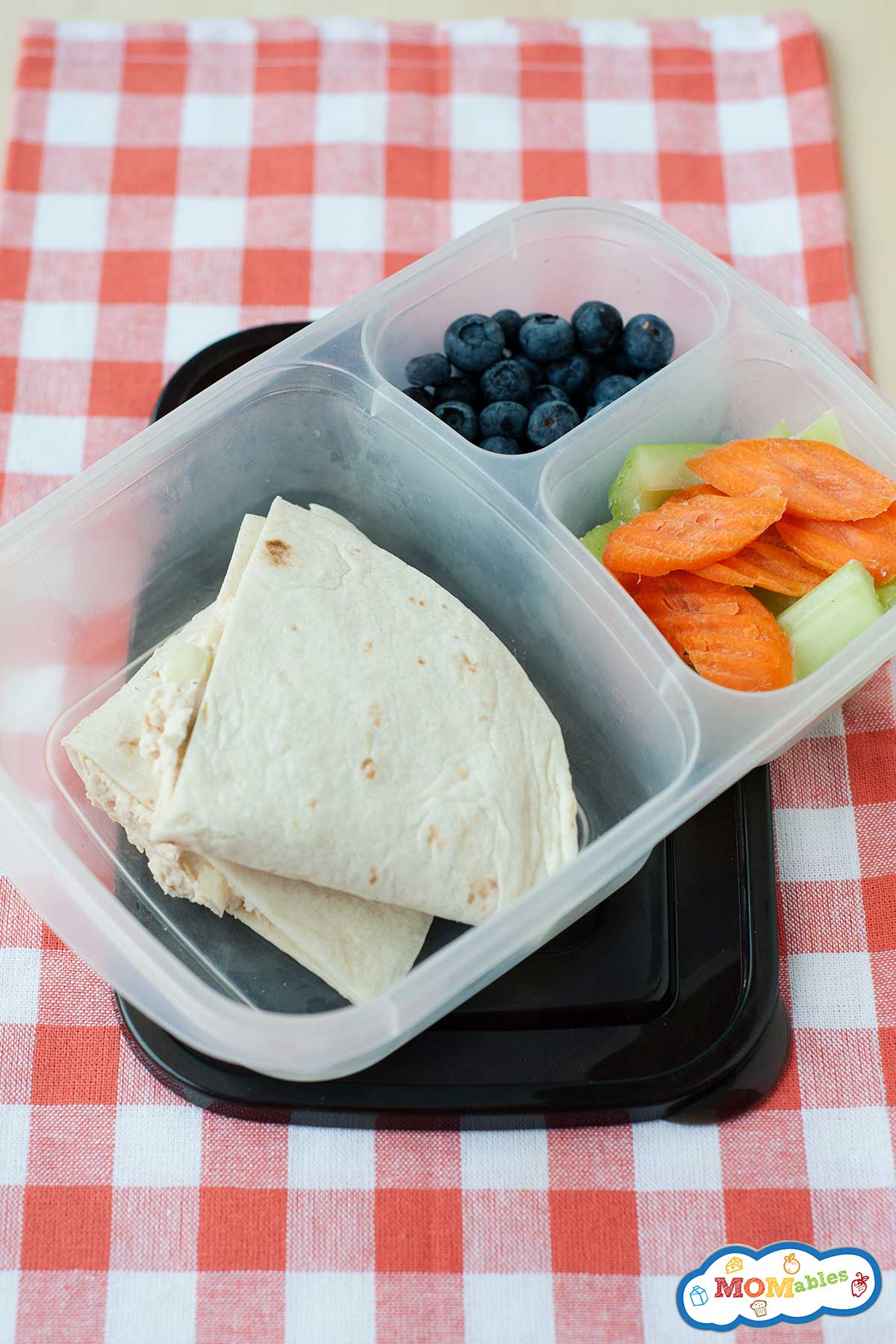 chicken salad quesadilla in a lunch container with carrot chips, sliced celery, and blueberries.