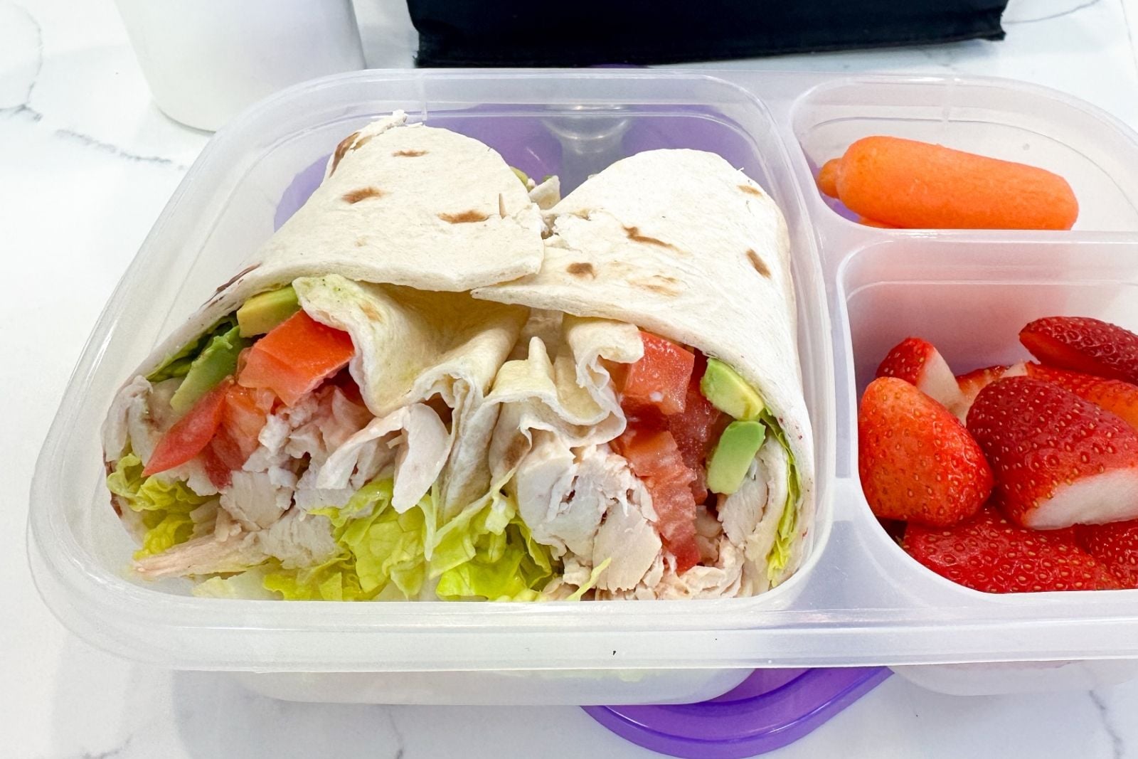 two halves of a chicken avocado wrap in a lunchbox