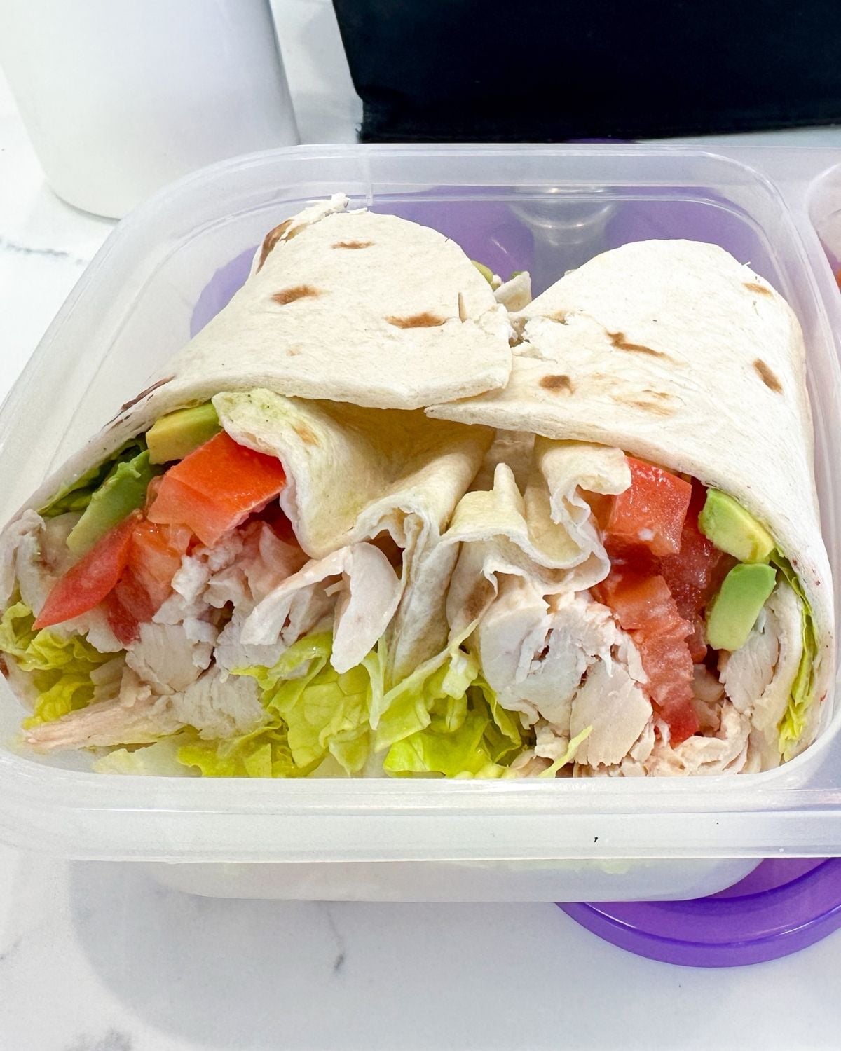 two halves of a chicken avocado wrap in a lunchbox