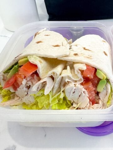 two halves of a chicken avocado wrap in a lunchbox