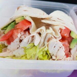 two halves of a chicken avocado wrap in a lunchbox