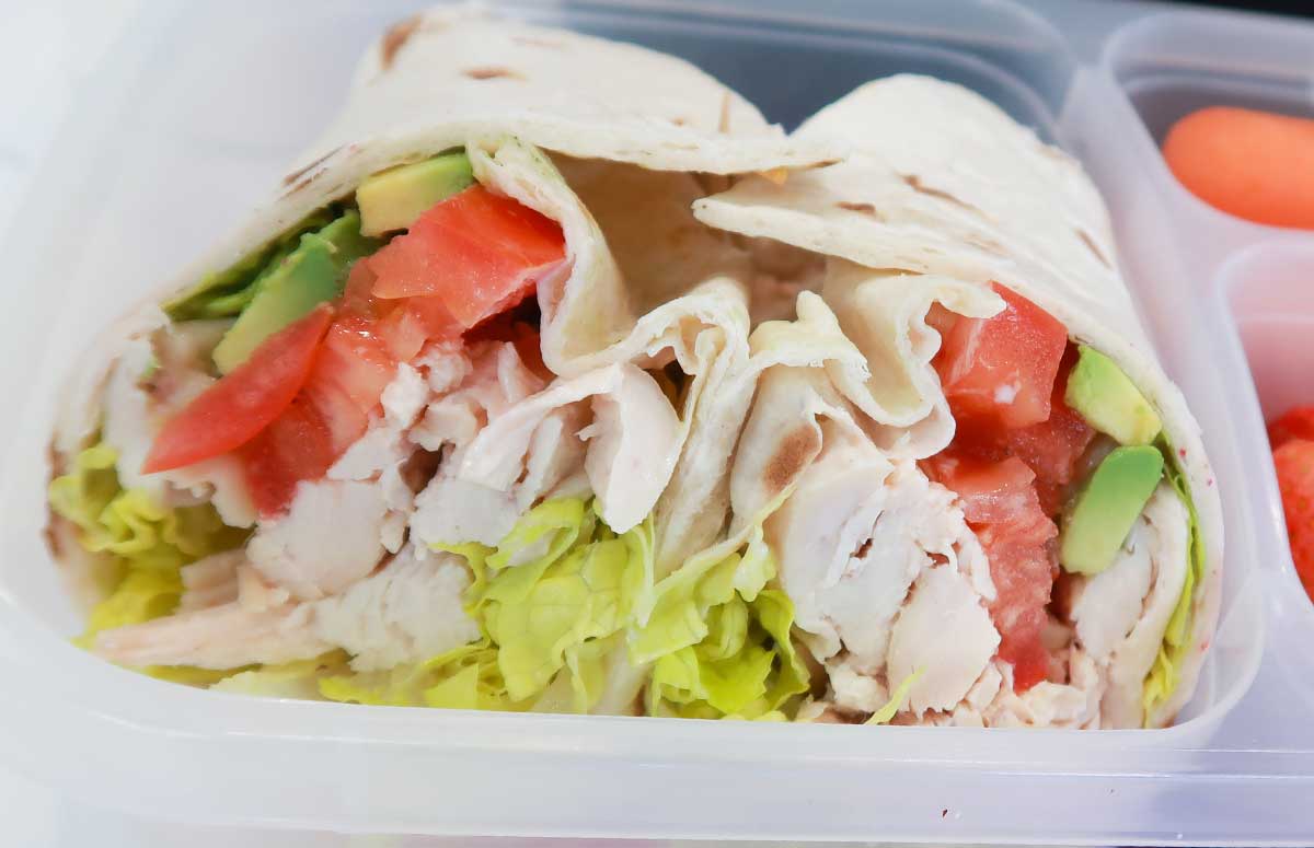 two halves of a chicken avocado wrap in a lunchbox 