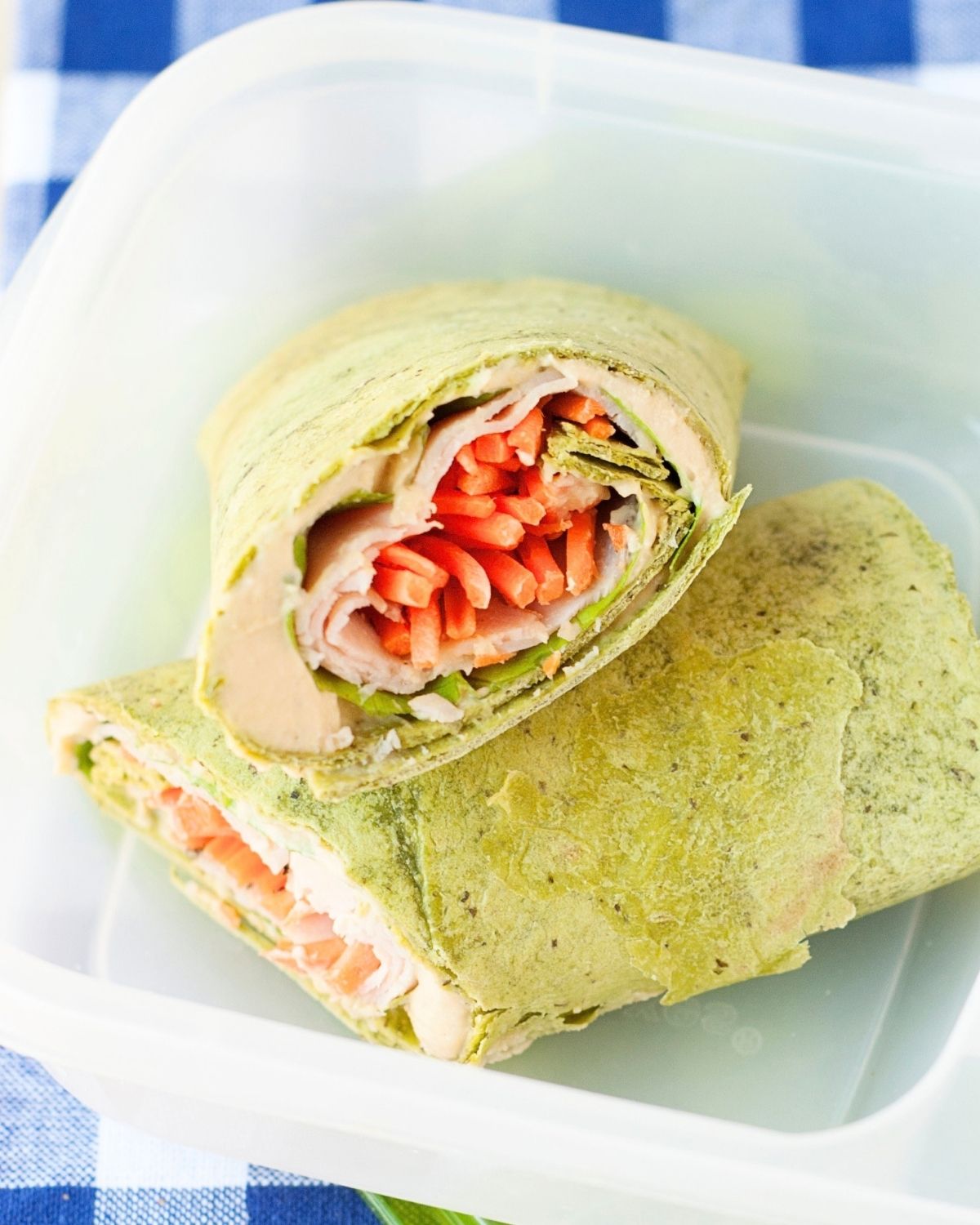 close up of a spinach wrap filled with turkey, hummus, and veggies
