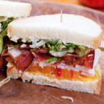 turkey sandwich with bacon, cheddar, tomato and lettuce sliced in halves