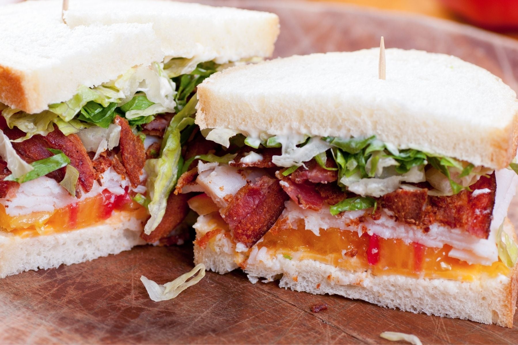 turkey sandwich with bacon, cheddar, tomato and lettuce sliced in halves