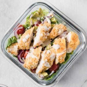 a glass lunch container with chicken strip salad