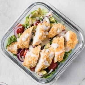 a glass lunch container with chicken strip salad